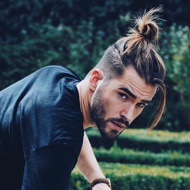 Contemporary man bun styled at crown with neat sides showing 2026 refinement